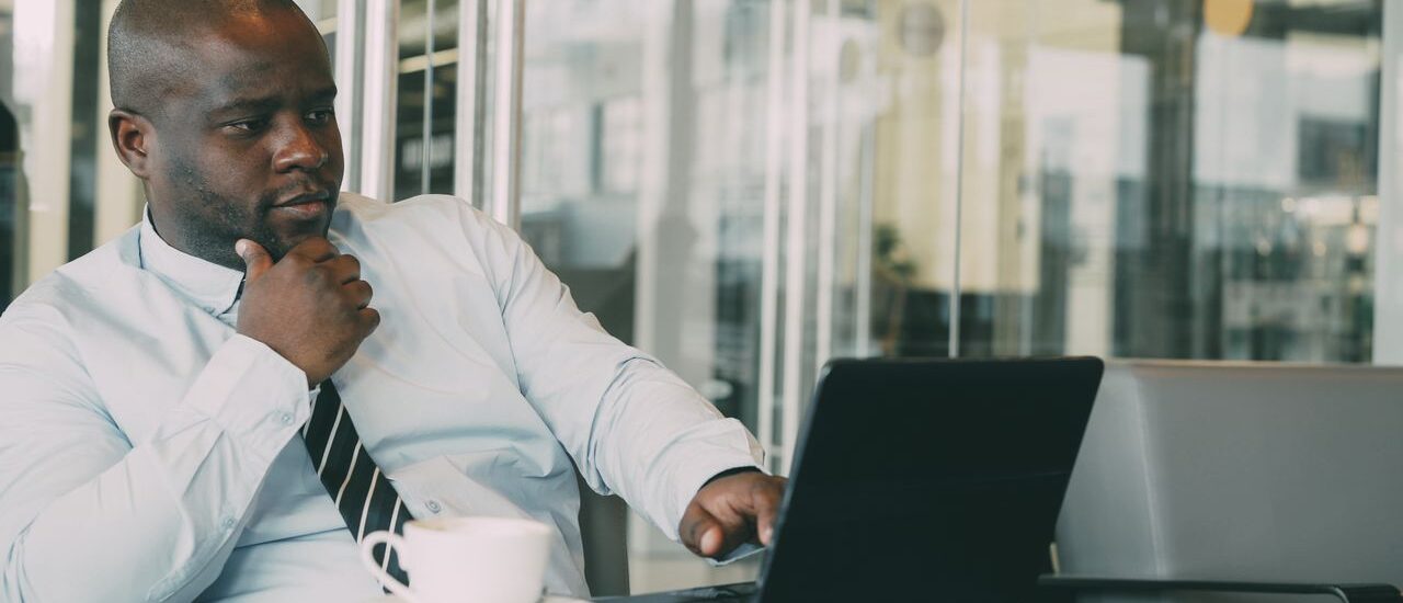 Busy executive working on laptop with coffee during high stress workday