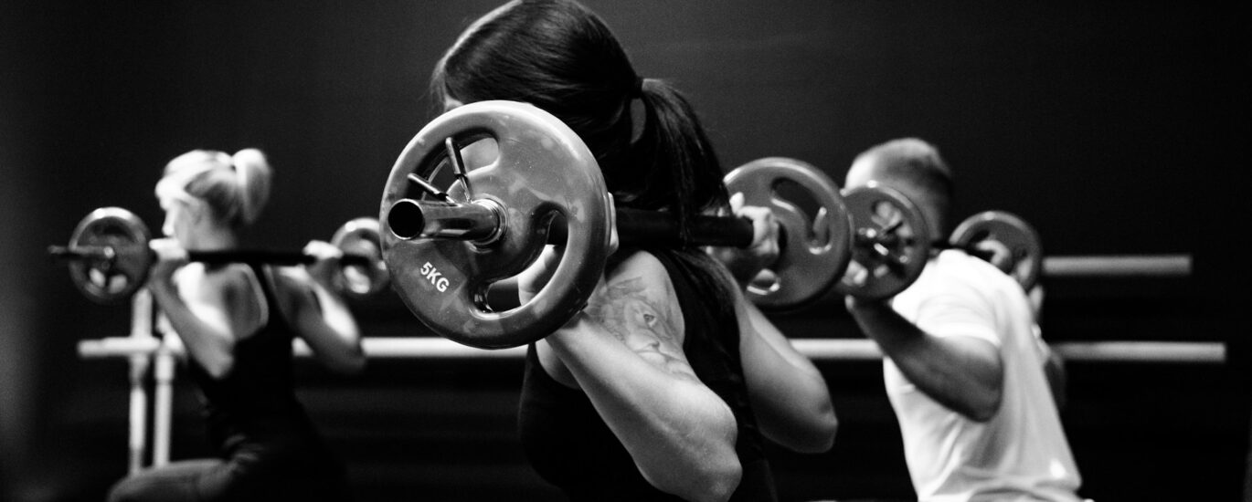 Group class doing weighted barbell squats for bone health after 40