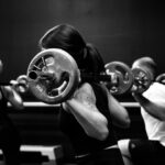Group class doing weighted barbell squats for bone health after 40