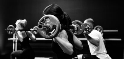 Group class doing weighted barbell squats for bone health after 40
