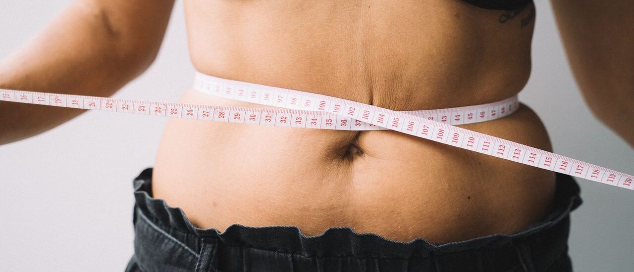 Woman measuring stress belly fat around midsection