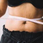 Woman measuring stress belly fat around midsection