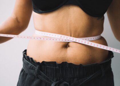 Woman measuring stress belly fat around midsection