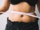 Woman measuring stress belly fat around midsection