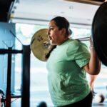 Woman over 40 practicing progressive overload with barbell back squats for muscle growth