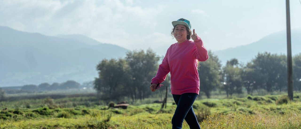 Active woman smiling and giving a thumbs up while walking outdoors for metabolic health and longevity