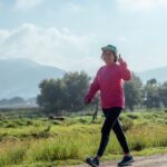 Active woman smiling and giving a thumbs up while walking outdoors for metabolic health and longevity