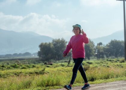 Active woman smiling and giving a thumbs up while walking outdoors for metabolic health and longevity