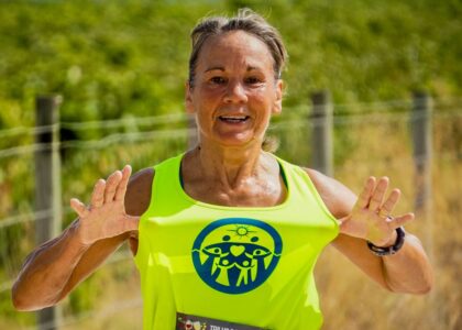 Active middle-aged woman smiling while jogging outdoors on a sunny day, representing healthy aging and fitness for mybestfit.net